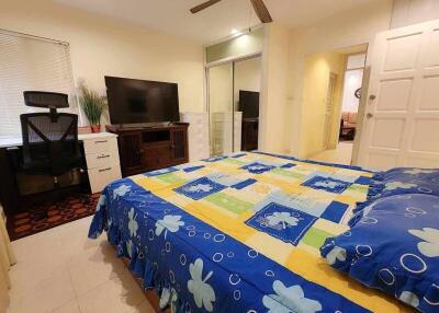 Bedroom with a colorful bedspread, desk, and mirror closet