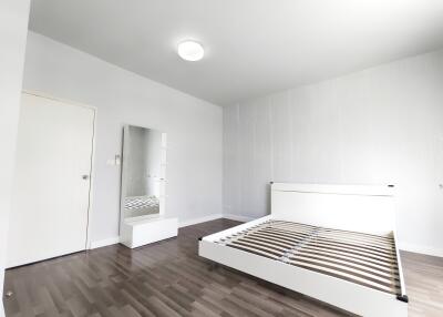 Bright, unfurnished bedroom with wooden floors and a bed frame