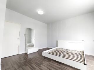 Bright, unfurnished bedroom with wooden floors and a bed frame