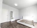 Bright, unfurnished bedroom with wooden floors and a bed frame