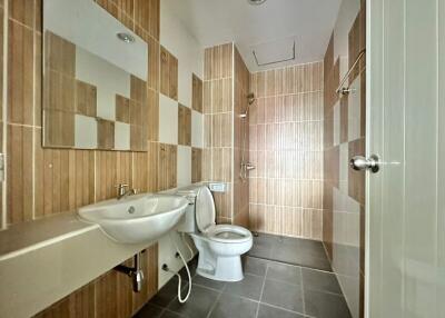 Modern bathroom with large tiles, wall-mounted sink, and toilet