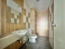 Modern bathroom with large tiles, wall-mounted sink, and toilet