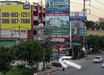 Street view of various commercial buildings with advertisements and a busy street