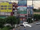 Street view of various commercial buildings with advertisements and a busy street