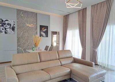 Modern living room with a beige sectional sofa, elegant curtains, and abstract wall art