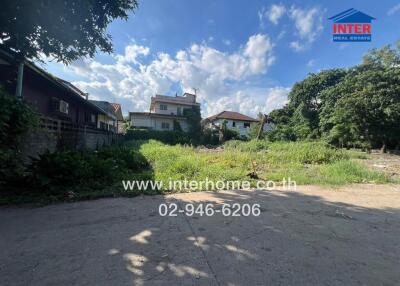 Open vacant lot with surrounding housing and vegetation