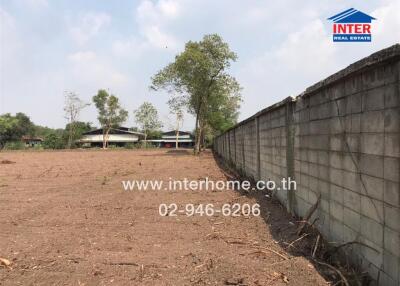 Empty land with a concrete wall and trees in the background