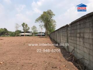 Empty land with a concrete wall and trees in the background