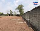 Empty land with a concrete wall and trees in the background