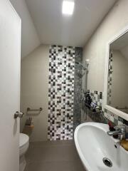 Modern bathroom with mosaic tiles, walk-in shower, and a vanity mirror