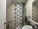 Modern bathroom with mosaic tiles, walk-in shower, and a vanity mirror