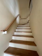 Well-lit interior staircase with wooden steps and handrails