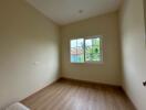 Empty bedroom with wooden flooring and a large window with an outdoor view