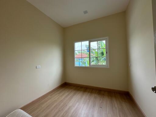 Empty bedroom with wooden flooring and a large window with an outdoor view