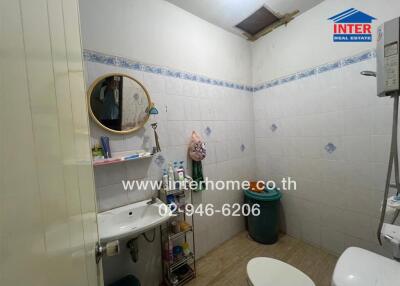 A well-maintained bathroom with a sink, storage shelves, mirror, and sanitary items.