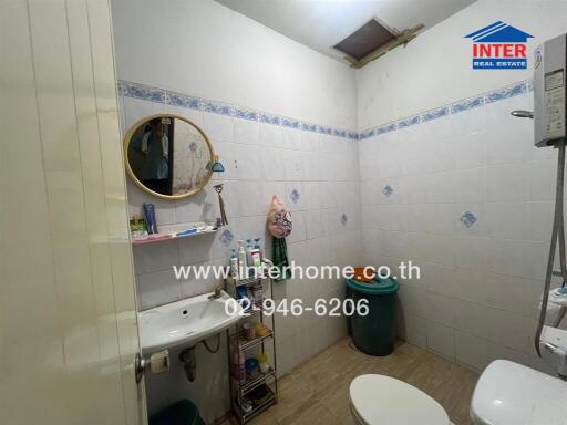 A well-maintained bathroom with a sink, storage shelves, mirror, and sanitary items.