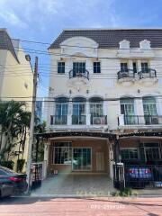 Front view of a three-story building with balconies and parking area