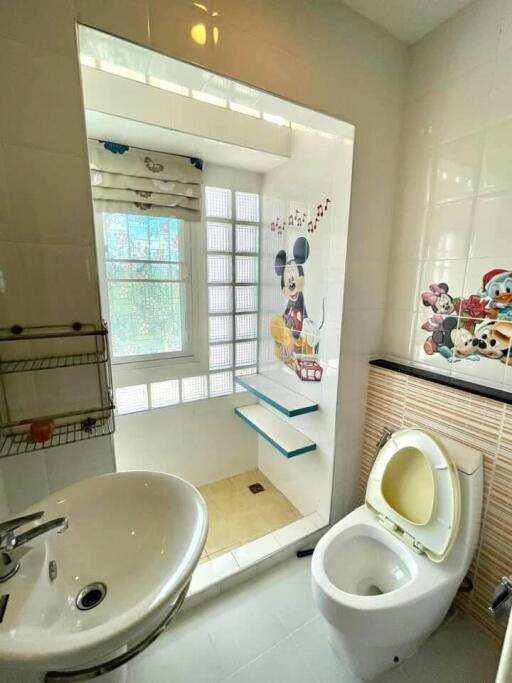 Bathroom with cartoon-themed decor, featuring a sink, toilet, and shower area