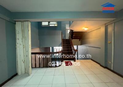 Main living area with tile flooring and wooden staircase