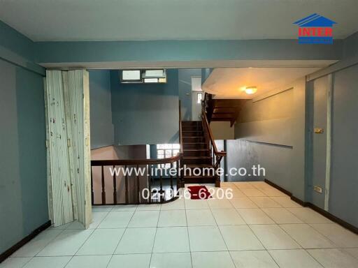 Main living area with tile flooring and wooden staircase