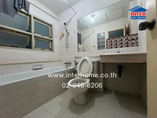 A bathroom with a bathtub, toilet, sink, and wall mirror