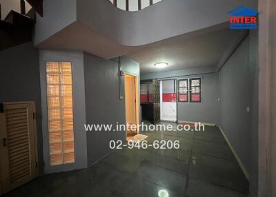 Interior view of a building with staircase, hallway, and kitchen area