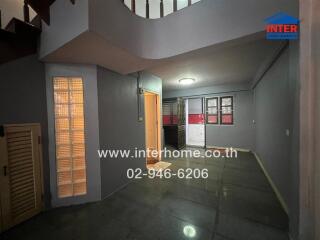 Interior view of a building with staircase, hallway, and kitchen area