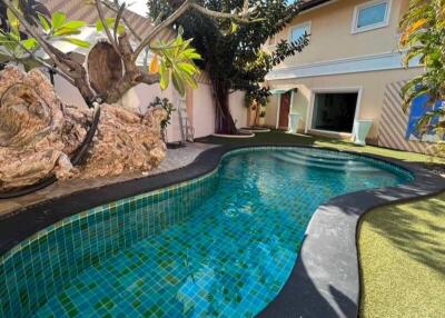 Swimming pool in an outdoor garden area with house in the background