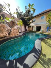 Swimming pool in an outdoor garden area with house in the background