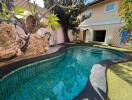 Swimming pool in an outdoor garden area with house in the background