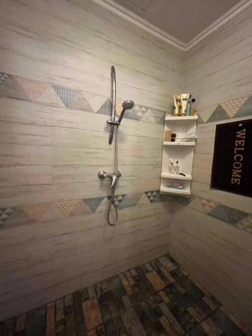 Shower area with wall-mounted shower head and storage shelf