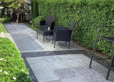 Outdoor seating area with paved walkway and lush greenery