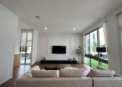 A modern living room with large windows and a wall-mounted TV