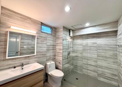 Modern bathroom with wood-grain tiles and glass shower