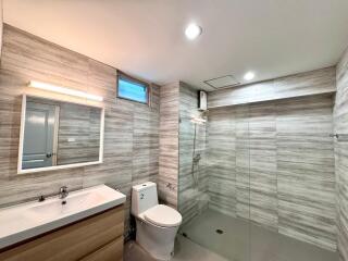 Modern bathroom with wood-grain tiles and glass shower