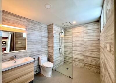 Modern bathroom with wooden paneling, glass shower, and contemporary fixtures