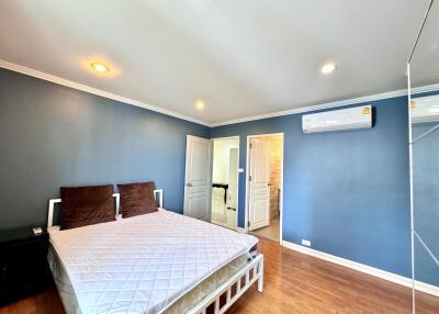 Spacious bedroom with blue walls, wooden flooring and modern lighting