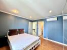 Spacious bedroom with blue walls, wooden flooring and modern lighting