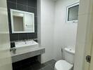 modern bathroom with a sink, mirror, toilet, and small window