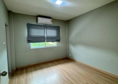 Spacious bedroom with wooden flooring and large window