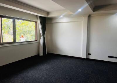 Spacious empty living room with large window and dark carpet