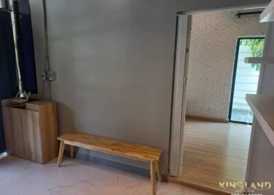 Photo of a living area with a wooden bench and view of another room