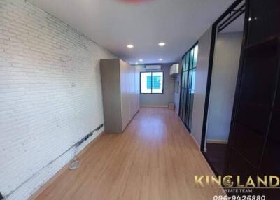 spacious modern bedroom with wooden flooring, white brick walls, built-in wardrobe, and large window