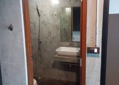 Bathroom with open shower, sink, and toilet