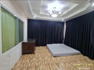 Spacious bedroom with wooden flooring and large curtains