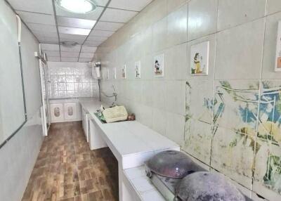 Long kitchen with tile flooring and ceiling, white walls, and cooking equipment