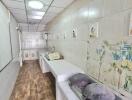 Long kitchen with tile flooring and ceiling, white walls, and cooking equipment