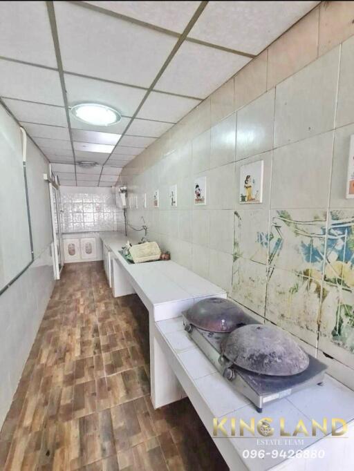 Long kitchen with tile flooring and ceiling, white walls, and cooking equipment