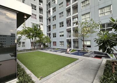 Exterior common area of apartment building with greenery and water features