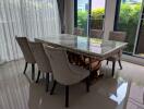 Modern dining area with six upholstered chairs and a large marble table